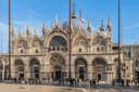 St. Mark’s Basilica in Venice featuring its ornate façade, golden mosaics, arches and domes overlooking St. Mark’s Square.